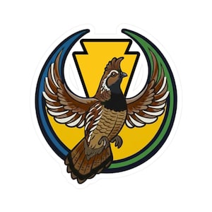 Op de afbeelding: Een sticker met een gestileerde kwartel met uitgespreide vleugels. De vogel is bruin, zwart en wit, tegen een gele driehoek en een blauwe en groene boog. Het ontwerp heeft een strakke, grafische stijl.