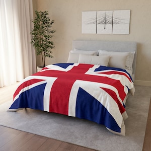 Pode incluir: Uma cama branca com uma manta de arremesso com padrão Union Jack vermelho, branco e azul. A cama tem uma cabeceira branca e dois travesseiros brancos.