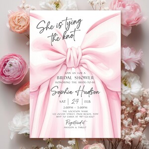 K&ouml;nnte beinhalten: Eine Einladung zur Brautparty mit einem gro&szlig;en rosa Schleifendesign und dem Text "She is tying the knot". Die Einladung enth&auml;lt Details f&uuml;r Sophia Hudsons Brautparty, umgeben von rosa und wei&szlig;en Blumen.
