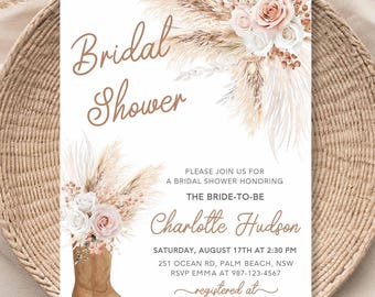 Pode incluir: Um convite para um chá de panela com tema rústico. O convite apresenta as palavras "Bridal Shower" em escrita elegante, juntamente com detalhes florais e de capim-dos-pampas. Uma bota de cowboy marrom é apresentada na parte inferior. O convite inclui detalhes do evento.