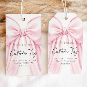 May include: Two custom gift tags with a pink bow design. The tags have the text "Custom Tag" and "Fully Editable" printed on them. The tags are rectangular and have a string attached.