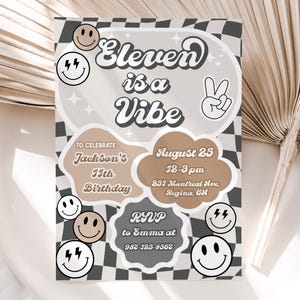 Op de afbeelding: Een zwart-wit geruite achtergrond met een bruine wolkvorm waarop in een retro-lettertype "Eleven is a Vibe" staat. De wolk heeft ook een vredesteken en smiley-gezichten. De tekst eronder zegt "To Celebrate Jackson's 11th Birthday" en "August 25 12-3 pm 255 Montreal Ave, Regina, Gl" met een telefoonnummer onderaan.