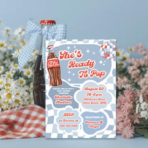 May include: A baby shower invitation with the text "She's Ready To Pop" in red and white. The invitation is light blue with a checkered pattern and features a cartoon Coca-Cola bottle. A Coca-Cola bottle with a blue bow is in the background.
