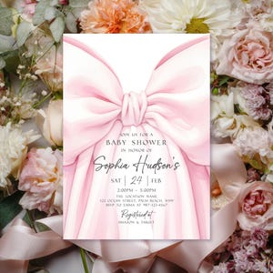 May include: A baby shower invitation featuring a large pink bow design. The invitation includes the text "Join us for a Baby Shower in Honor of Sophia Hudson's" with event details. The invitation is surrounded by floral arrangements.