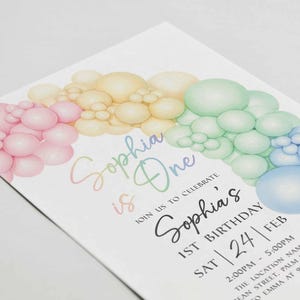 May include: A pastel-colored birthday invitation with a rainbow balloon design. The invitation reads "Sophia is One" and includes details for a first birthday celebration, including the date, time, and location.