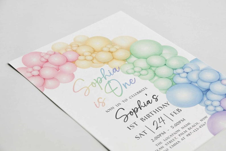 May include: A pastel-colored birthday invitation with a rainbow balloon design. The invitation reads "Sophia is One" and includes details for a first birthday celebration, including the date, time, and location.