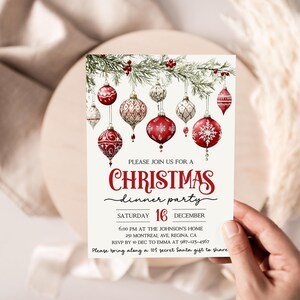 May include: A Christmas dinner party invitation with a red and white color scheme. The invitation features a watercolor illustration of red and white ornaments hanging from a pine branch. The text reads "Please join us for a Christmas dinner party, Saturday 16 December, 6:00 PM at the Johnson's Home, 25 Montreal Ave, Regina, CA, RSVP by 10 Dec to Emma at 97-123-4567, Please bring along a $10 secret Santa gift to share."