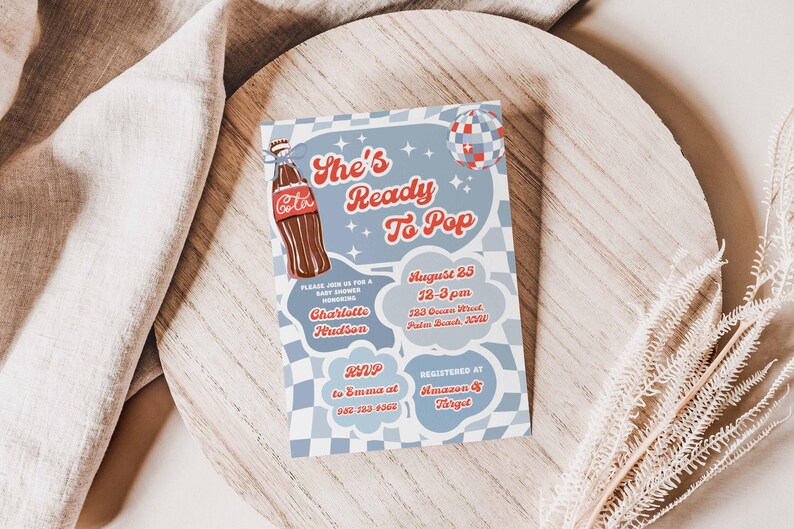 May include: A baby shower invitation with a retro design. The invitation features the text "She's Ready To Pop" in red script, along with a Coca-Cola bottle illustration. Additional text includes the date, time, location, and RSVP information.