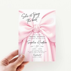 K&ouml;nnte beinhalten: Rosa Brautparty-Einladung mit dem Text "She is tying the knot". Die Einladung zeigt eine gro&szlig;e rosa Schleife und enth&auml;lt Details f&uuml;r die Veranstaltung, wie Datum, Uhrzeit und Ort.
