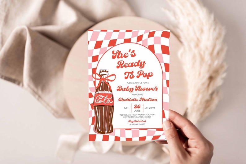 May include: Baby shower invitation with a retro design. The invitation features a brown soda bottle illustration with the word "Cola" and the text "She's Ready To Pop". The invitation is decorated with a red and pink checkered pattern.