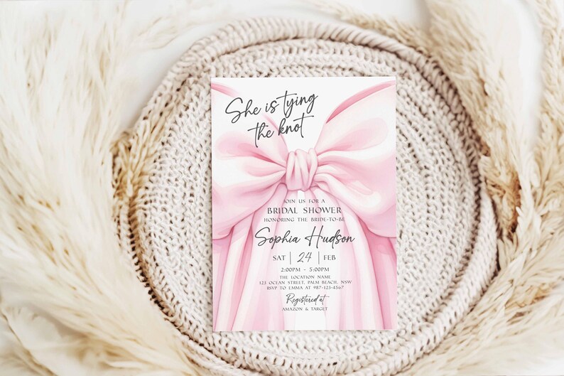 K&ouml;nnte beinhalten: Eine Einladung zur Brautparty mit einem gro&szlig;en rosa Schleifendesign. Der Text "She is tying the knot" steht oben, mit Details zur Veranstaltung darunter, einschlie&szlig;lich des Namens der Braut, Datum und Uhrzeit. Die Einladung befindet sich vor einem neutralen Hintergrund.