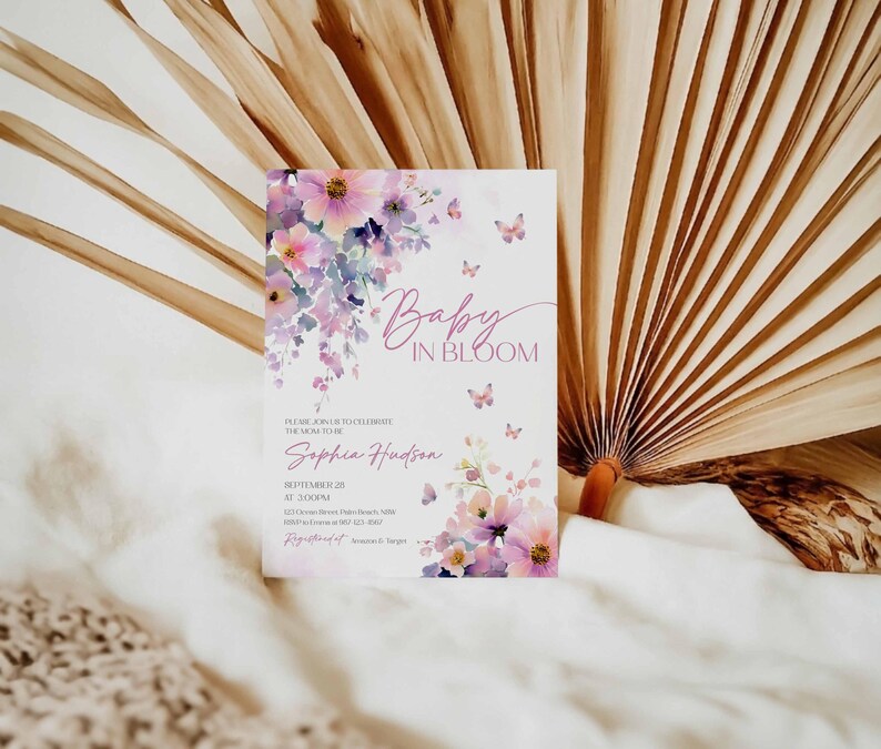 Może przedstawiać: Zaproszenie na baby shower z ilustracjami kwiat&oacute;w i motyli. Zaproszenie zawiera tekst "Baby in Bloom" oraz szczeg&oacute;ły wydarzenia, w tym imię Sophia Hudson oraz datę i godzinę. Projekt zawiera kolory r&oacute;żowy, fioletowy i biały.
