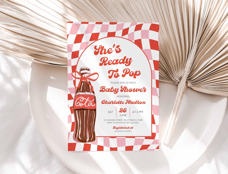 May include: A baby shower invitation with a retro design. The invitation features a brown cola bottle with a red bow, set against a red and pink checkered background. Text includes "She's Ready To Pop" and baby shower details.