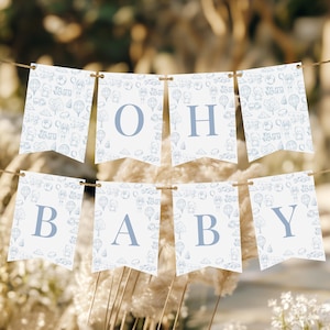 Może przedstawiać: Niebiesko-biały baner na baby shower z nadrukiem "Oh Baby". Baner jest ozdobiony wzorem balonów na gorące powietrze, chmur i gwiazd.