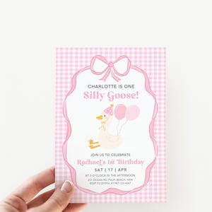 May include: Pink and white gingham patterned invitation with a white goose wearing a party hat and holding balloons. The text reads "Charlotte is one Silly Goose!" and "Join us to celebrate Rachael's 1st Birthday SAT 17 APR at 3 o'clock in the afternoon 251 Ocean Rd, Palm Beach, NSW RSVP to Emma at 987-123-4567"