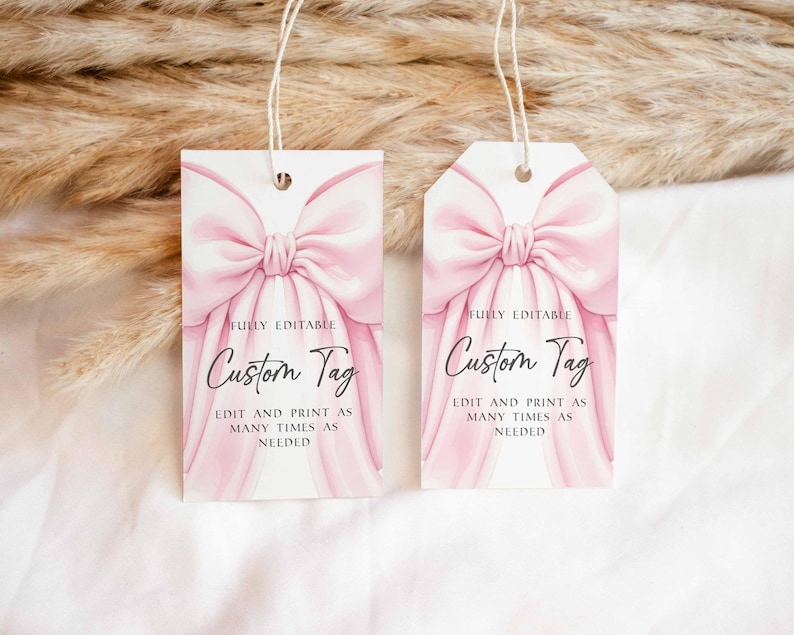 May include: Two custom gift tags with a pink bow design. The tags have the text "Custom Tag" and "Fully Editable" printed on them. The tags are rectangular and have a string attached.