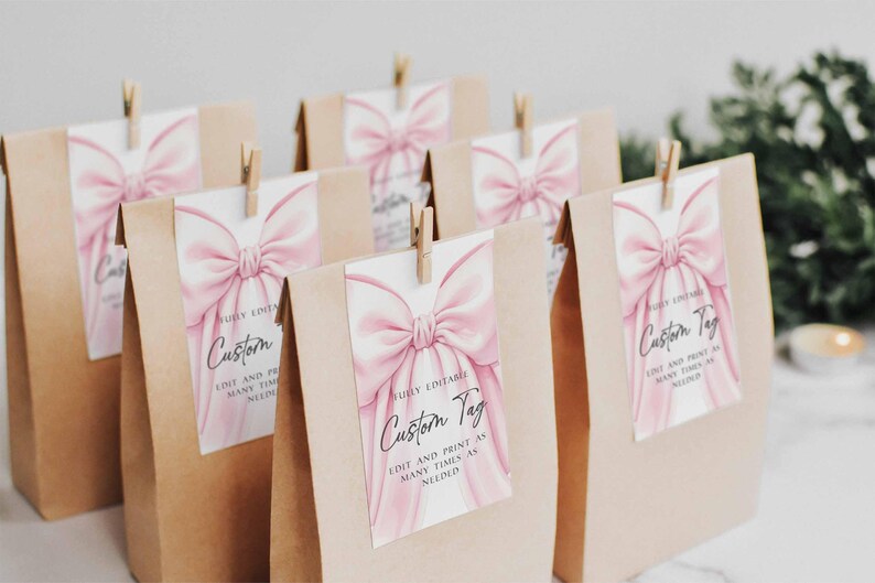 May include: Several kraft paper gift bags with custom tags. Each tag features a watercolor pink bow design and the words "Custom Tag". The tags are held in place with small wooden clothespins.