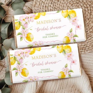 May include: Two white chocolate bar wrappers featuring a lemon and floral design. The text on the wrappers reads "Madison's bridal shower" and "Thanks for coming!"