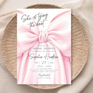 K&ouml;nnte beinhalten: Eine rosa Brautparty-Einladung mit dem Text "She is tying the knot" und dem Namen "Sophia Hudson". Die Einladung zeigt eine gro&szlig;e rosa Schleife und liegt auf einem geflochtenen Korb.