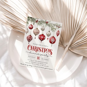 May include: A Christmas dinner party invitation with a watercolor illustration of red and gold ornaments hanging from a pine branch. The text reads "Please join us for a Christmas dinner party, Saturday, December 16, 6:00 PM at the Johnson's Home, 30 Montreal Ave, Regina, CA, RSVP by Dec 10 to Emma at 587-123-4567, Please bring along a $10 secret Santa gift to share."