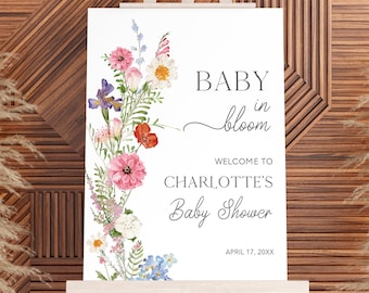 May include: A white sign with watercolor floral border and the text "BABY in bloom"  "WELCOME TO CHARLOTTE'S Baby Shower"  "APRIL 17, 20XX"