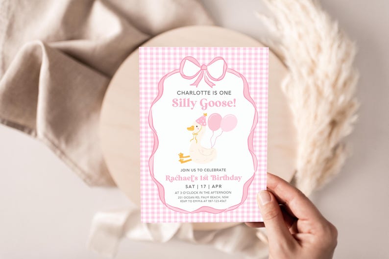 May include: Pink and white gingham patterned invitation with a pink bow and a cartoon goose wearing a pink party hat. The text reads "Charlotte is one Silly Goose!" and "Join us to celebrate Rachael's 1st Birthday Sat | 17 | Apr at 2 o'clock in the afternoon 31 Ocean Rd, Palm Beach, NSW RSVP to Emma at 123 456"