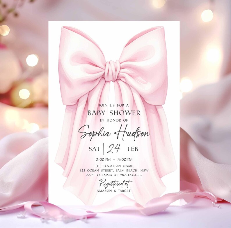 Op de afbeelding: Een babyborrel uitnodiging met een grote, roze strik in aquarel stijl. De uitnodiging bevat de tekst "Doe mee voor een babyborrel ter ere van Sophia Hudson" met evenementdetails en RSVP-informatie. Geregistreerd bij Amazon & Target.