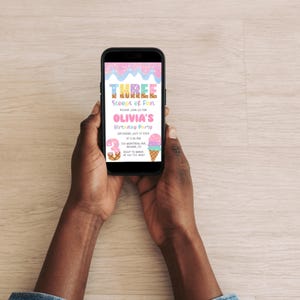 May include: A smartphone displays a colorful birthday party invitation. The invitation reads "THREE Scoops of Fun" and features ice cream cone illustrations. The invitation is for Olivia's birthday party.