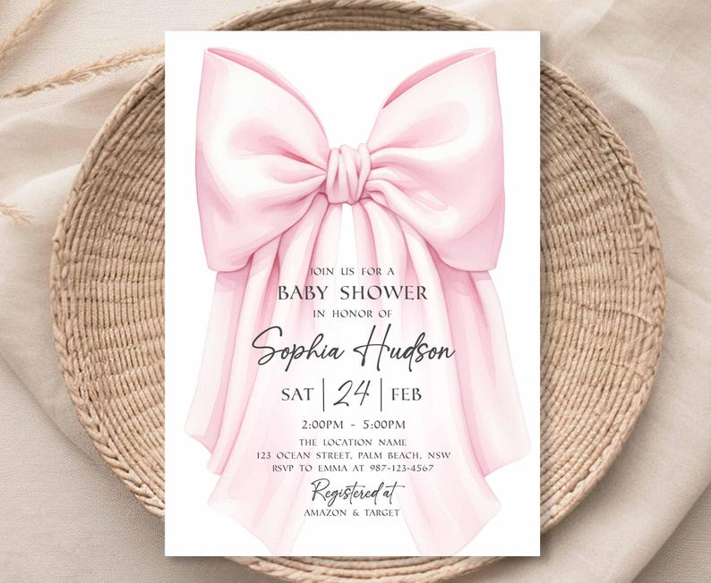 Op de afbeelding: Een uitnodiging voor een babyshower met een grote, lichtroze strik bovenaan. De uitnodiging bevat de tekst "Doe met ons mee voor een babyshower ter ere van Sophia Hudson" en evenementdetails. De uitnodiging staat op een neutrale achtergrond.
