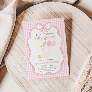May include: Pink and white gingham patterned invitation with a cartoon goose wearing a crown and holding balloons. The text reads "Charlotte is one Silly Goose!" and "Join us to celebrate Rachael's 1st Birthday Sat 17 Apr at 3 o'clock in the afternoon".