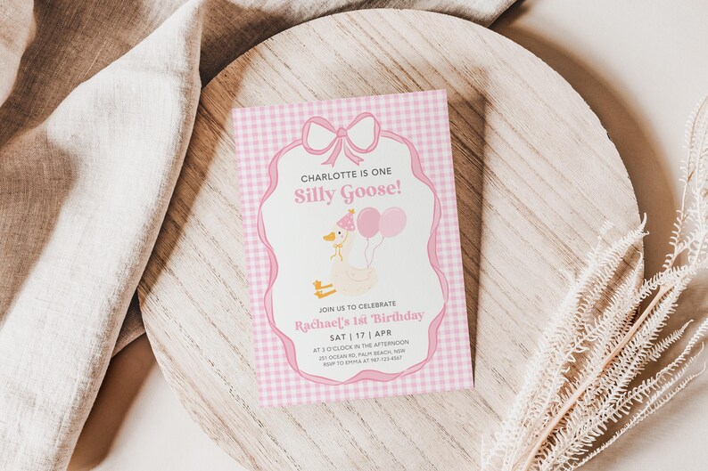 May include: Pink and white gingham patterned invitation with a cartoon goose wearing a crown and holding balloons. The text reads "Charlotte is one Silly Goose!" and "Join us to celebrate Rachael's 1st Birthday Sat 17 Apr at 3 o'clock in the afternoon".