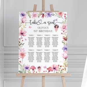 Könnte beinhalten: Ein floral gestalteter Sitzplan für eine erste Geburtstagsfeier. Der Plan zeigt eine fantasievolle Feenillustration und den Text "take a seat Olivia's 1st Birthday". Der Plan ist in acht Tische unterteilt, wobei für jeden Tisch Namen aufgelistet sind.