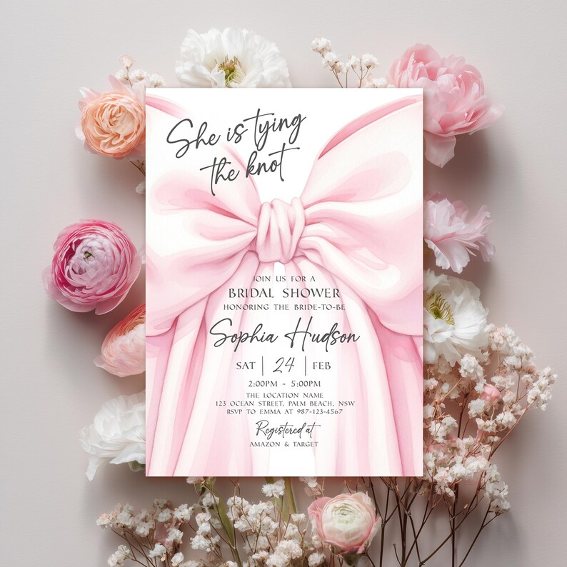 K&ouml;nnte beinhalten: Eine Einladung zur Brautparty mit einem gro&szlig;en rosa Schleifendesign und dem Text "She is tying the knot". Die Einladung enth&auml;lt Details f&uuml;r Sophia Hudsons Brautparty, umgeben von rosa und wei&szlig;en Blumen.