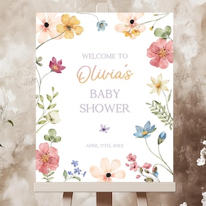 Op de afbeelding: Een wit welkomsbord met bloemillustraties in roze, gele en blauwe tinten. De tekst luidt "Welkom op Olivia's Baby Shower, 17 april 20XX".