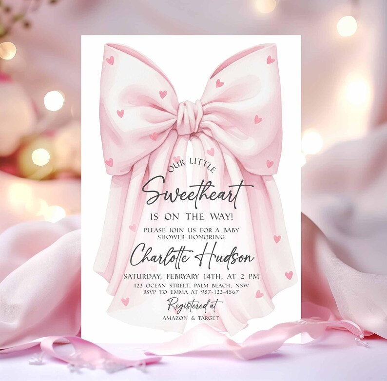 May include: A baby shower invitation featuring a large pink bow adorned with small pink hearts. The invitation reads "Our Little Sweetheart is on the way!" and includes details for Charlotte Hudson's baby shower, including date, time, and location.