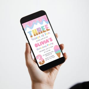 May include: A smartphone displays a colorful birthday party invitation. The invitation reads "THREE Scoops of Fun" and includes details for Olivia's party, featuring ice cream cone and donut graphics. The phone is held against a white background.