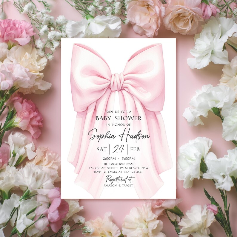 Op de afbeelding: Een babyborrel uitnodiging met een roze strik. De uitnodiging bevat de tekst "Doe met ons mee voor een babyshower ter ere van Sophia Hudson" met datum, tijd en locatie. Omringd door roze en witte bloemen.