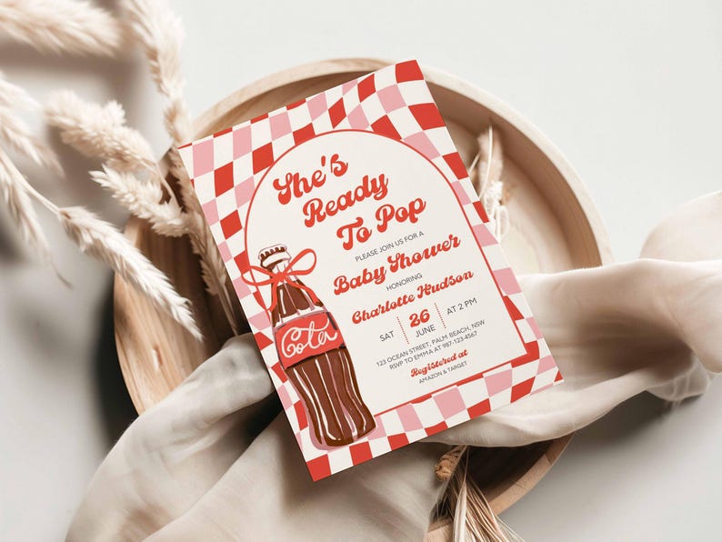 May include: A baby shower invitation with a retro design. The invitation features a red and pink checkered border and a vintage cola bottle illustration. Text includes "She's Ready To Pop" and details for the event.