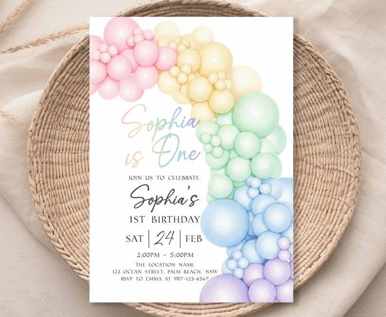 May include: A birthday invitation with a rainbow balloon arch design. The text "Sophia is One" is displayed in a script font. Additional text includes the date, time, and location for the celebration.