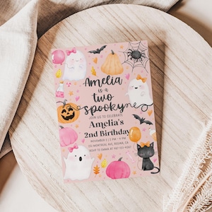 May include: A pink Halloween-themed invitation with the text "Amelia is a two spooky" and details for a second birthday celebration. The design includes ghosts, pumpkins, bats, and a black cat.