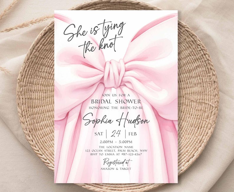 K&ouml;nnte beinhalten: Eine rosa Brautparty-Einladung mit einer gro&szlig;en Schleife. Die Einladung enth&auml;lt den Text "She is tying the knot" sowie Details zur Veranstaltung, einschlie&szlig;lich des Namens der Braut, Datum, Uhrzeit und Ort. Die Einladung ist bei Amazon & Target registriert.