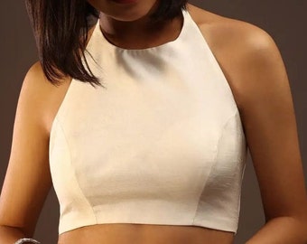 May include: A white halter top with a simple design. The top is made of a smooth, silky fabric.