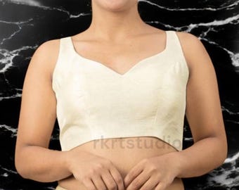 May include: A white sleeveless blouse with a sweetheart neckline. The blouse is made of a soft, silky fabric and has a cropped fit.