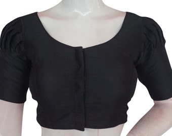 Könnte beinhalten: Eine schwarze Bluse mit kurzen Ärmeln, einem runden Ausschnitt und einem Knopfverschluss. Die Ärmel haben einen gerafften, bauschigen Look.