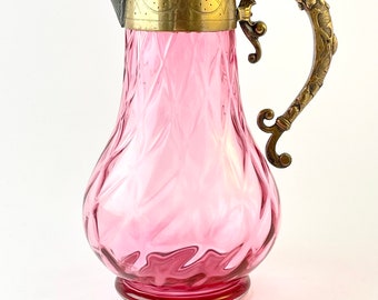 Handblown Cranberry Glass Pitcher With Ornate Brass Plated Metal Rim and Handle