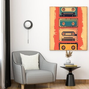 Op de afbeelding: Een retro-stijl wandkunstprint met een reeks kleurrijke cassettebandjes op een rode en oranje achtergrond. De print is ingelijst en hangt aan een witte muur.