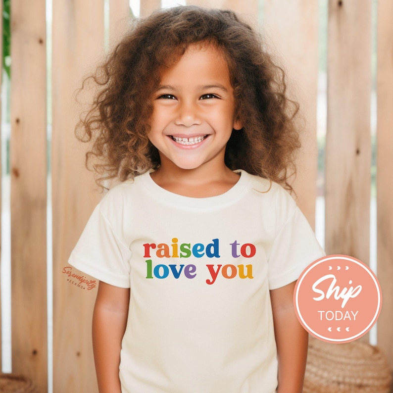 a little girl wearing a t - shirt that says raised to love you