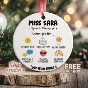 May include: A white ceramic Christmas ornament with a red ribbon. The ornament features the text "MISS SARA Speech Therapist thank you for..." and various icons with phrases like "Letting me shine" and "Finding my voice".