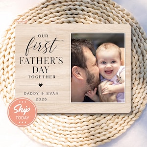 May include: Wooden photo frame with the text "Our First Father's Day Together" and a photo of a father and baby. The frame includes the names "Daddy & Evan" and the year 2026.