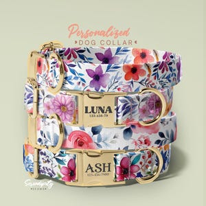 May include: Stacked personalized dog collars with floral patterns in purple, red, and pink. Each collar has a gold-colored buckle with a name and phone number. The collars are white with blue and green leaves.